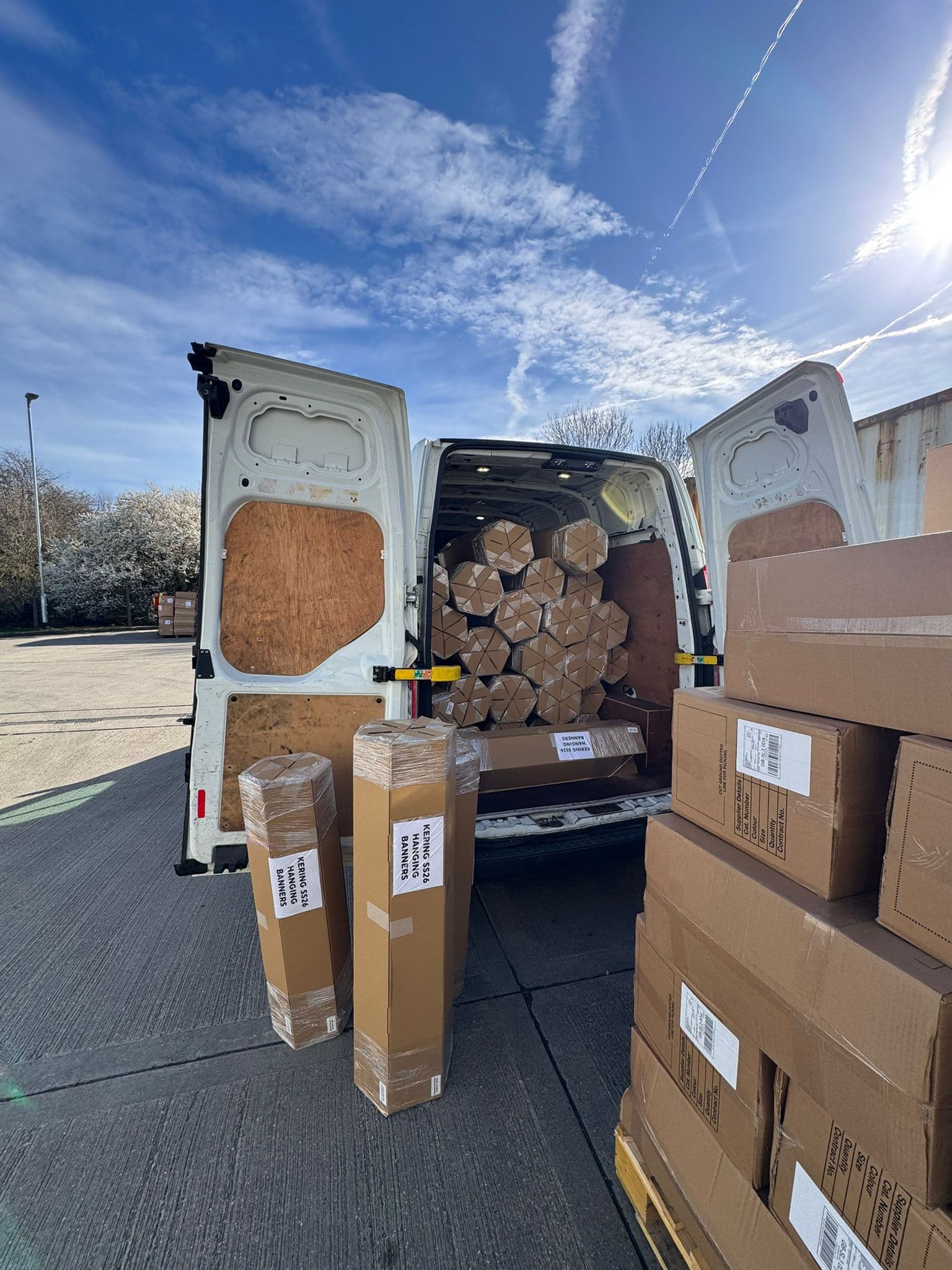 Rear of van packed with stacked boxes under clear sky — trade supply run